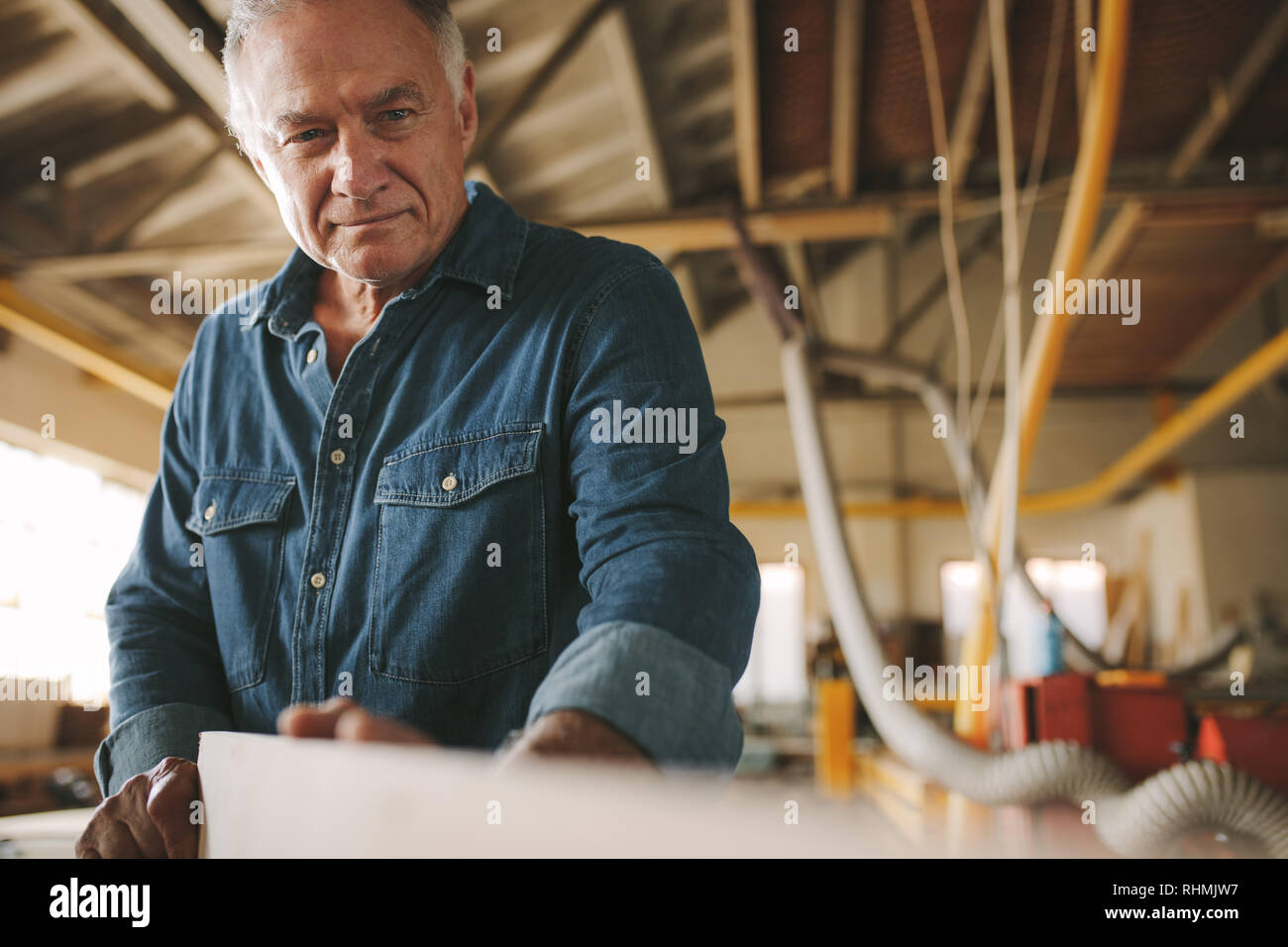Senior Handwerker in Holz, die Kontrolle auf Geradheit. Reife männliche Tischler Vorbereitung Möbel in seiner Werkstatt. Stockfoto