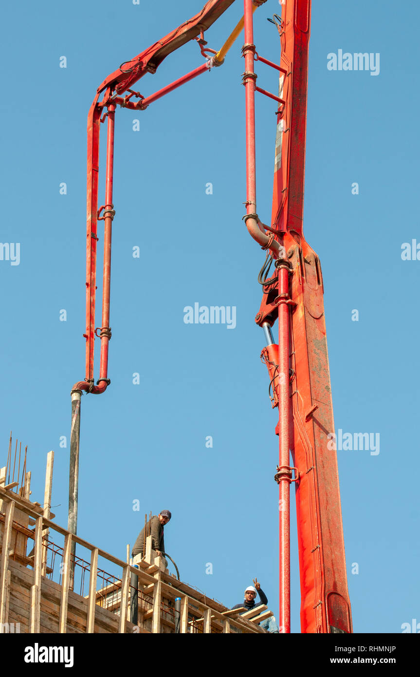 Orange Betonpumpe mit einem blauen Himmel Hintergrund auf einer Baustelle Stockfoto