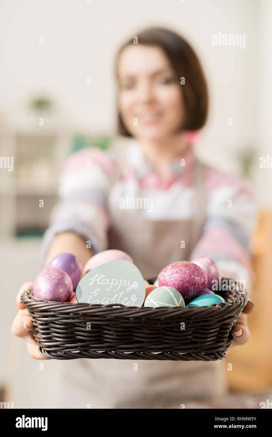 Haufen bunt bemalte Ostereier und kleine Karte im Korb von jungen casual Frau hielt Stockfoto