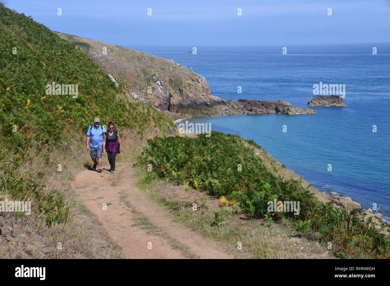 Ein paar Wanderer Wandern im Sonnenschein an der Küste entlang in Richtung Rosiere Schritte auf Herm Insel, Channel Islands.de. Stockfoto
