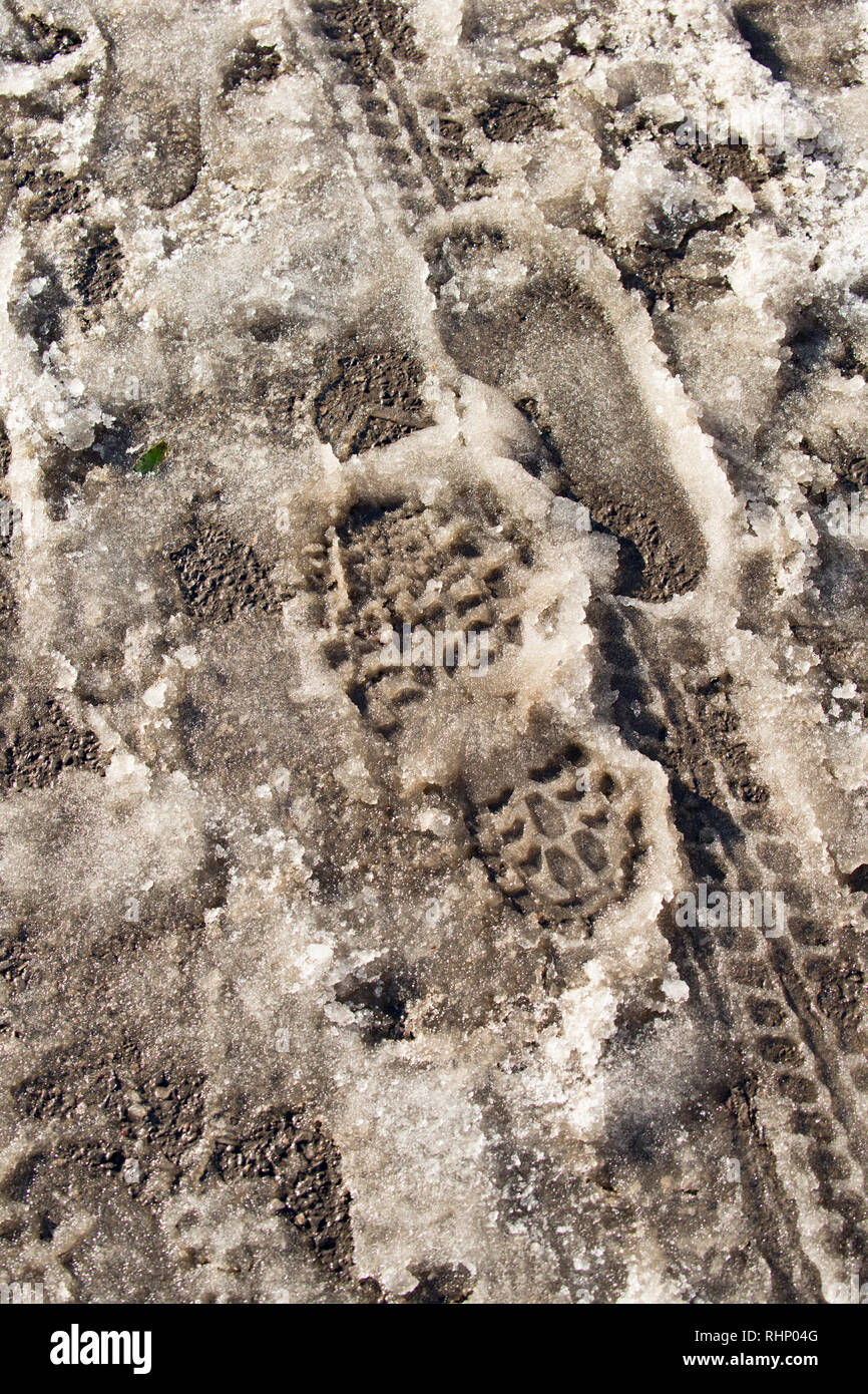 Footprints und Fahrrad Reifen Markierungen auf einer verschneiten Pflaster bei Frost. North Dorset England UK GB Stockfoto