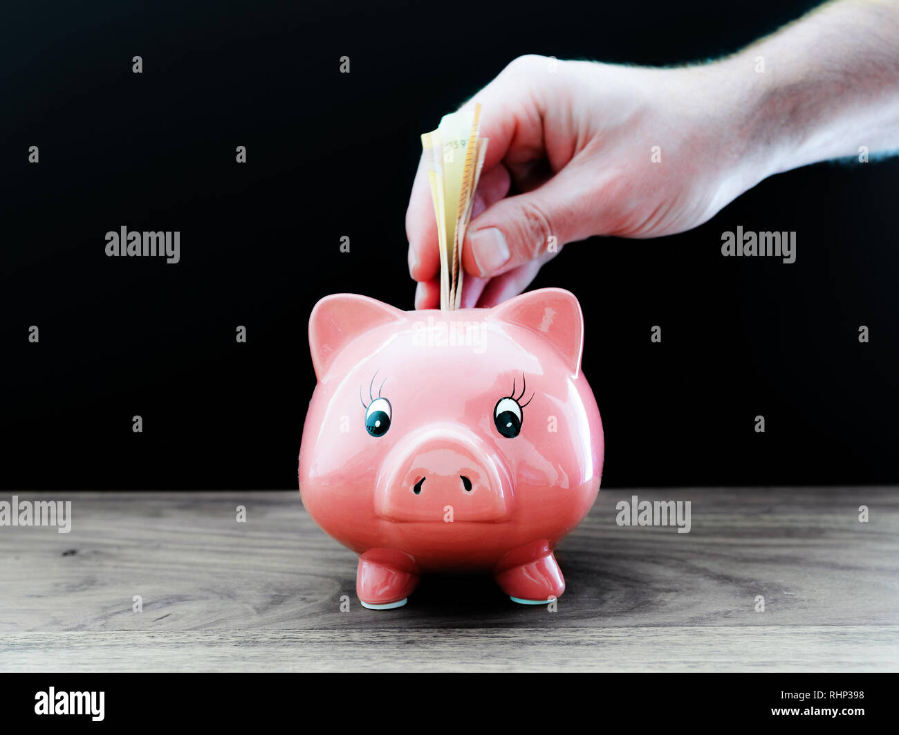 Hand Geld in piggy Bank Stockfoto