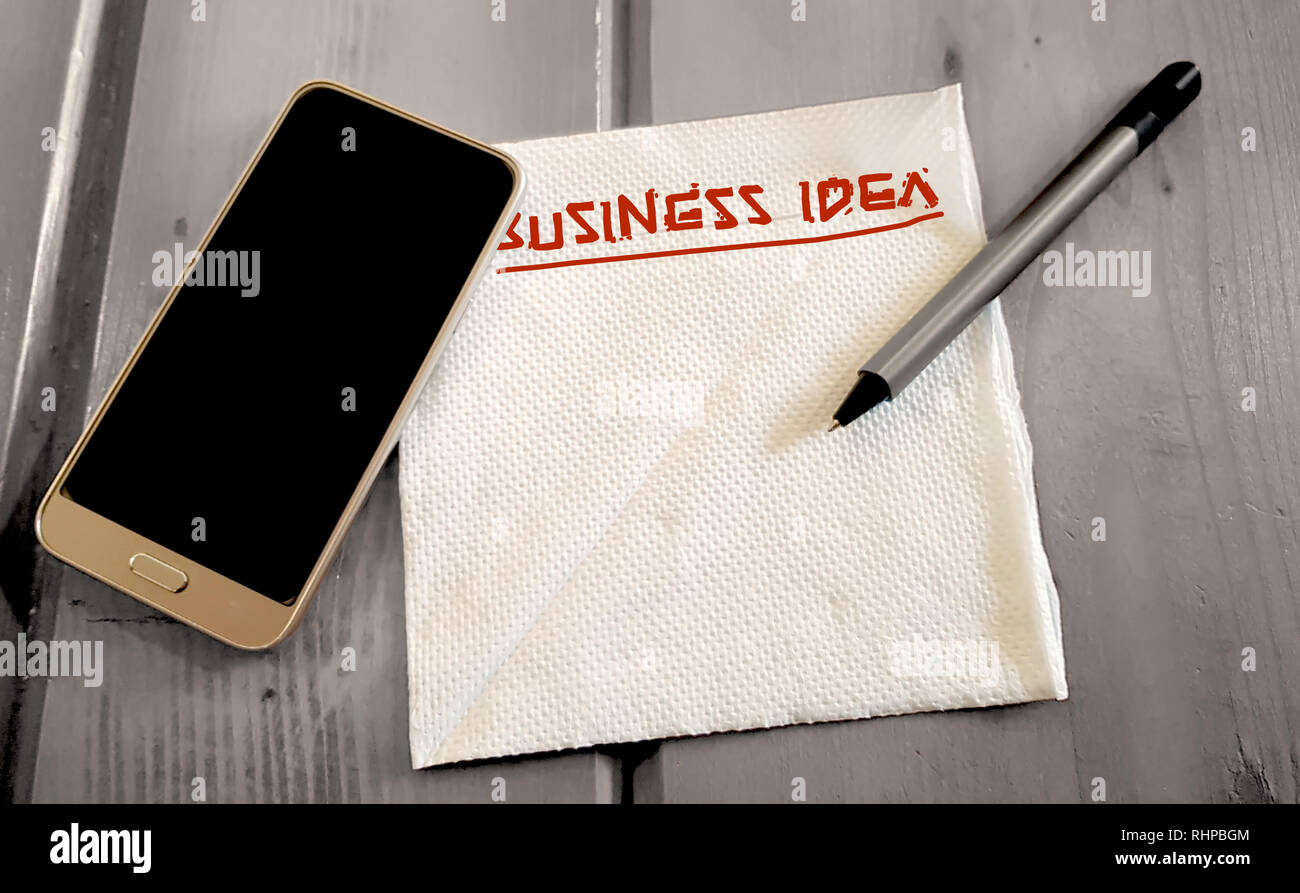 Business Startup Idea Note auf dem Papier Serviette mit Handy und Stift, auf einer hölzernen Oberfläche Stockfoto