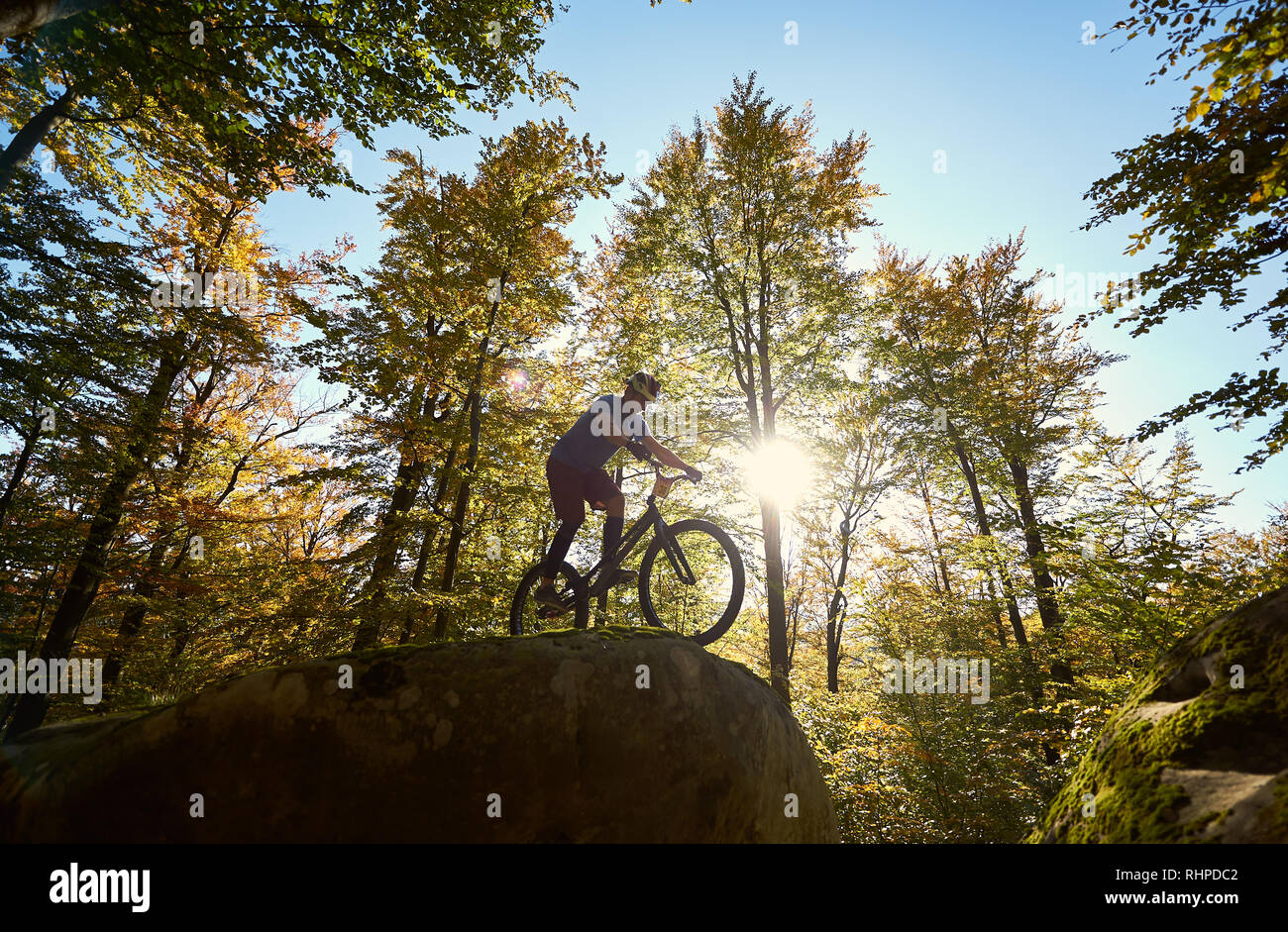 Aktive männliche Radfahrer reiten auf Trial Fahrrad, akrobatische Tricks auf Big Boulder im Wald im Sommer im Freien sonnigen Tag. Konzept der extremen gefährlicher Sport Stockfoto