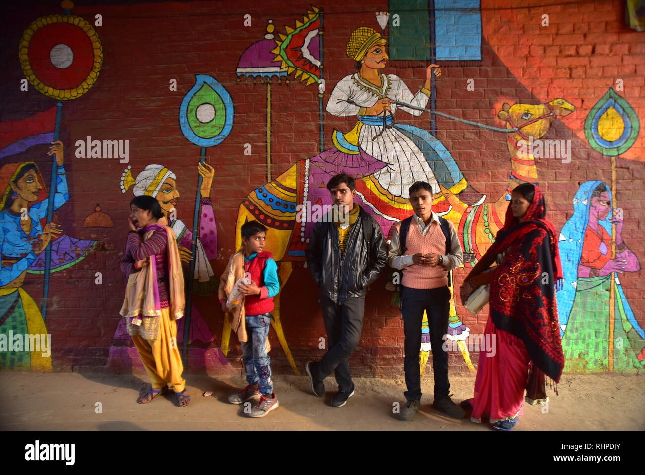 Pilger neben einer Wand mit Gemälden während der Wallfahrt gesehen. Kumbh Mela, einer der größten Gemeinde des Menschen auf der Erde. 3 crore Leute werden erwartet am Tag der zweiten Shahi Snan am 4. Februar und Arrangements sind entsprechend in Prayagraj gemacht. Stockfoto