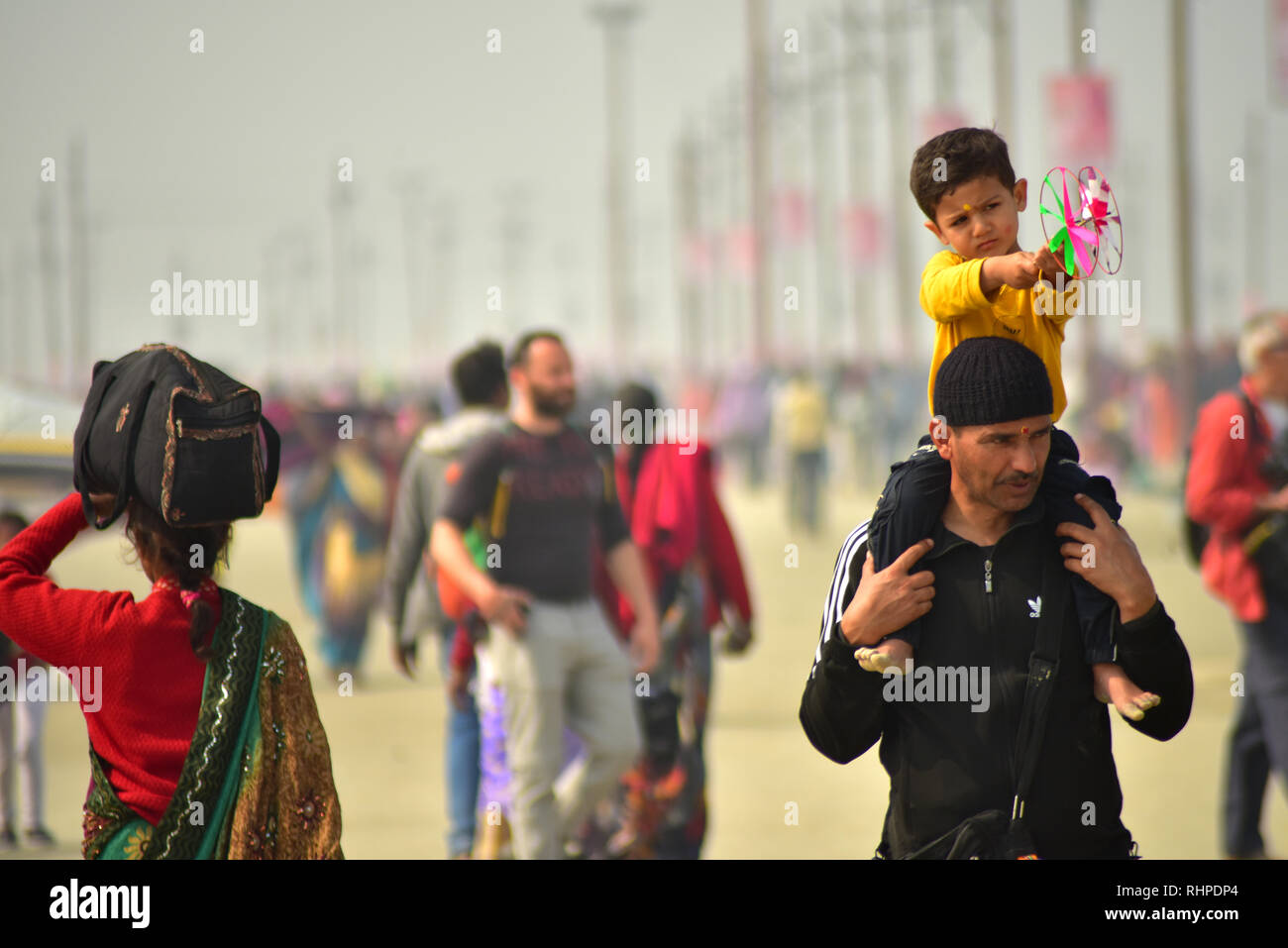 Ein Mann gesehen, der ein Kind auf seinen Schultern während der Wallfahrt. Kumbh Mela, einer der größten Gemeinde des Menschen auf der Erde. 3 crore Leute werden erwartet am Tag der zweiten Shahi Snan am 4. Februar und Arrangements sind entsprechend in Prayagraj gemacht. Stockfoto