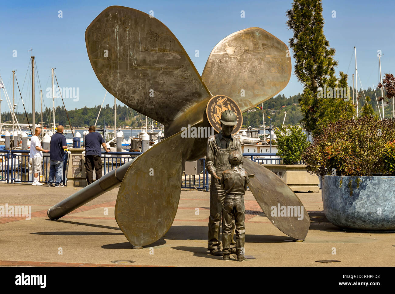 BREMERTON, WA, USA - JUNI 2018: Großes Metall Skulptur von einer Schiffsschraube, Arbeiter und Sohn auf der Promenade in der Nähe des Hafens in Bremerton, WA. Stockfoto