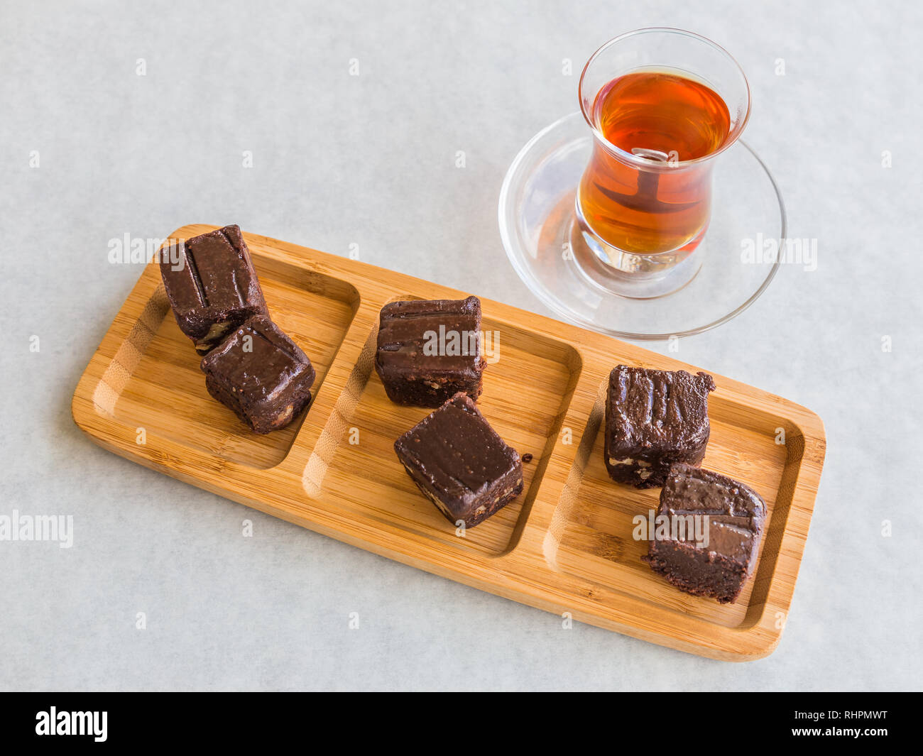 Schokolade Kuchen in Quadrate geschnitten und serviert auf einem Board mit Türkischem Tee in einem tee Glas. Stockfoto