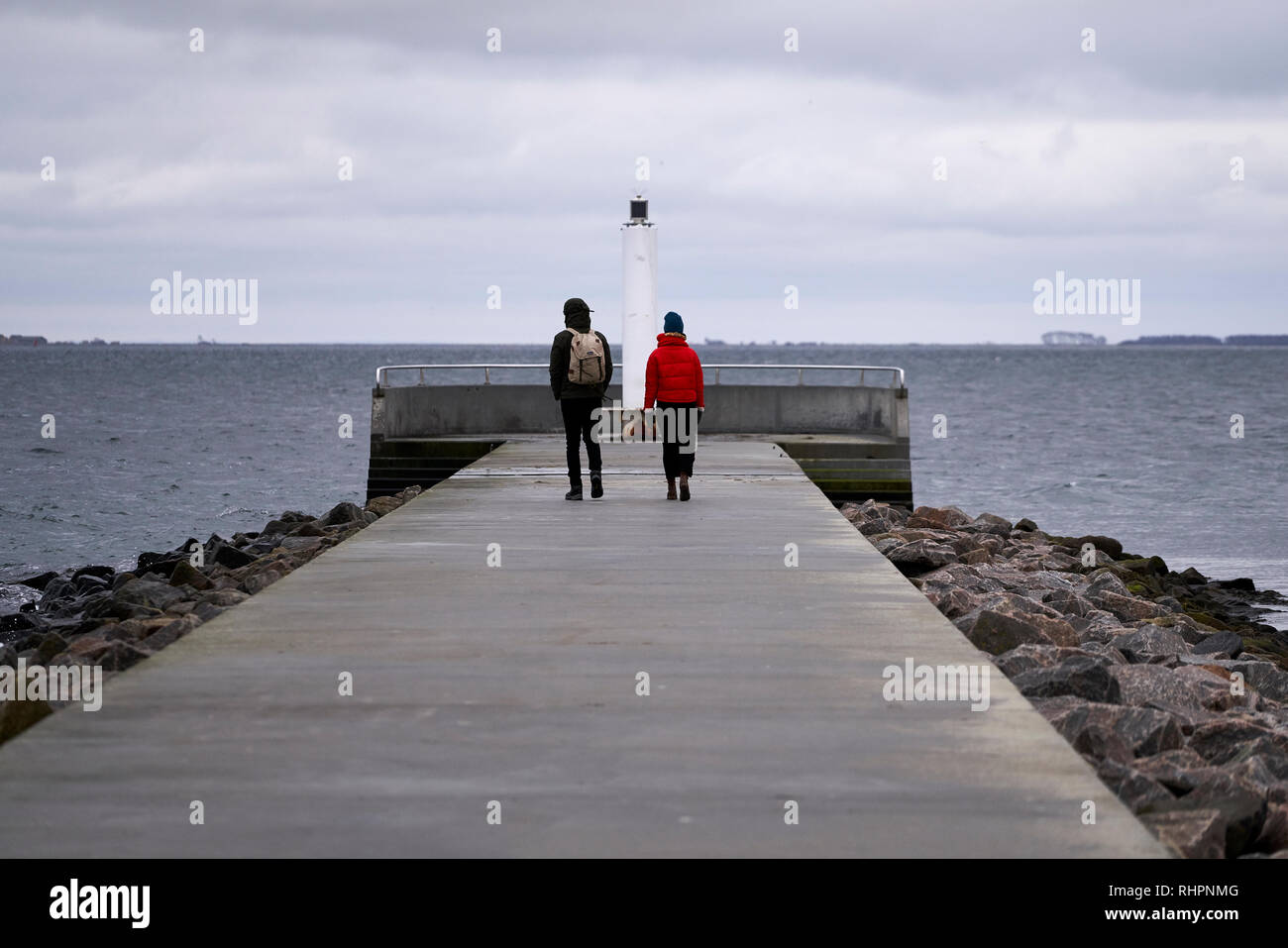 Paar stehend auf einem Pier mit Blick auf das Meer, Kopenhagen, Dänemark, Januar 2019 Stockfoto