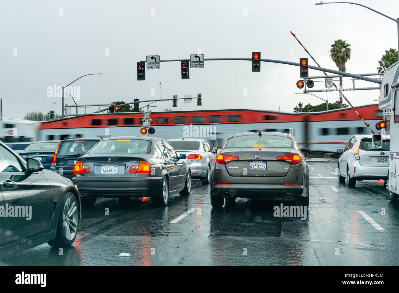 Februar 2, 2019 Sunnyvale/CA/USA - Fahrzeuge warten an einer roten Ampel; high speed Zug passiert im Hintergrund, San Francisco Bay Area, C Stockfoto