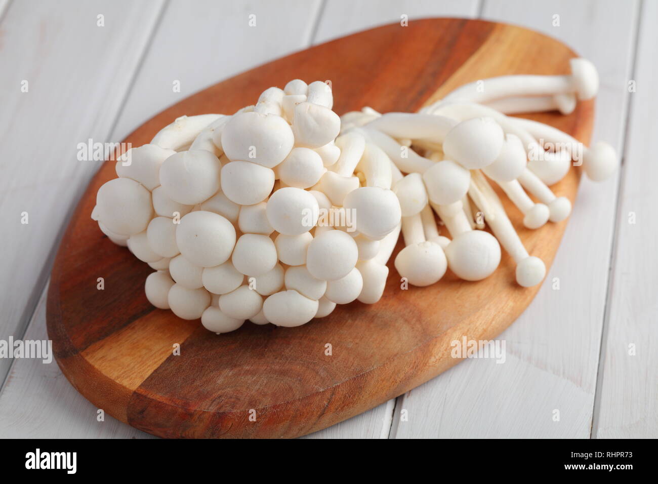 Bündel von raw Shimeji Pilze auch als Weiße buche Pilze bekannt auf einer hölzernen Schneidebrett Stockfoto
