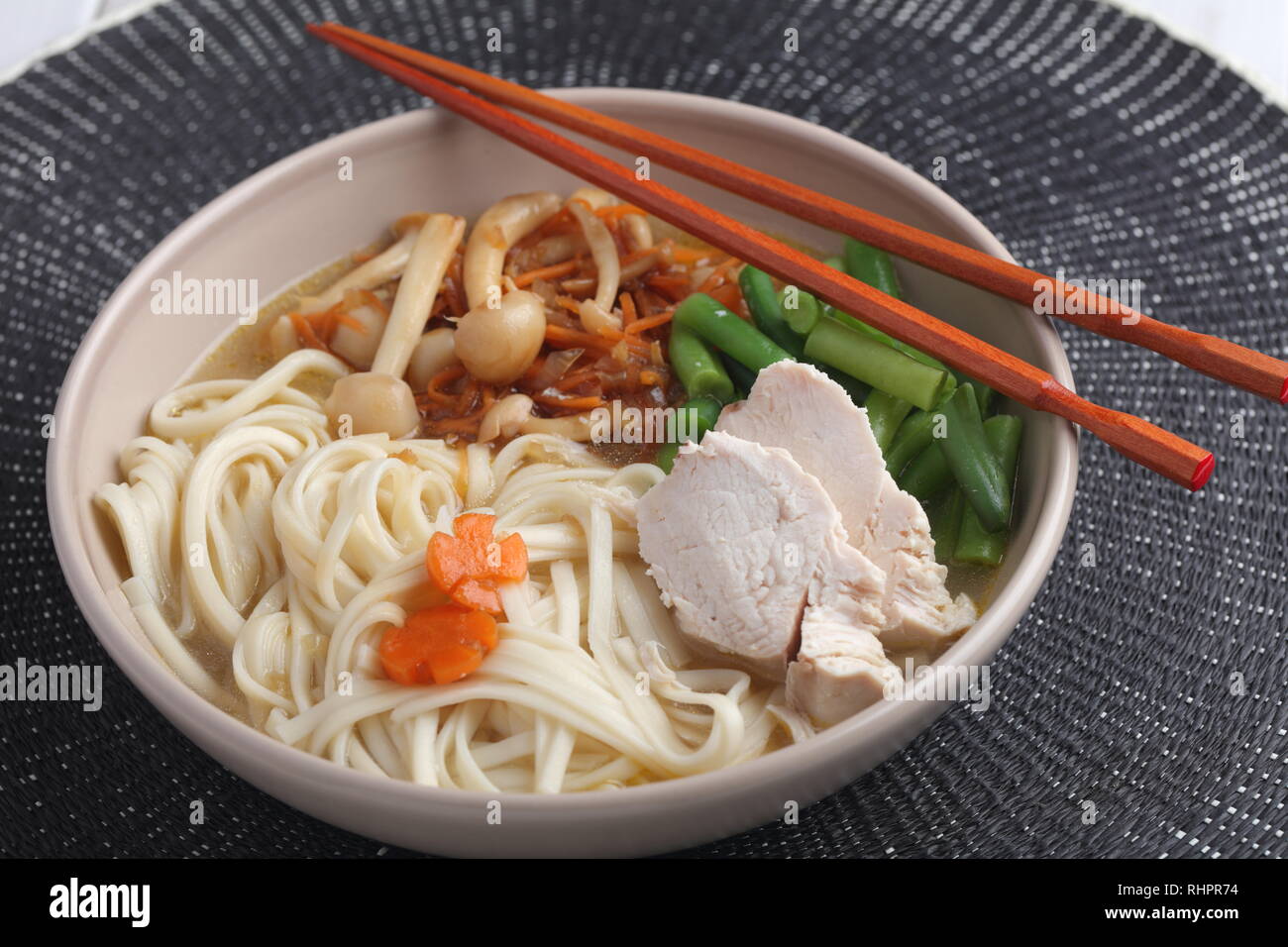 Huhn und Udon Noodle Soup mit Shimeji Champignons, Karotten, Zwiebeln, Spargel Bohnen Stockfoto