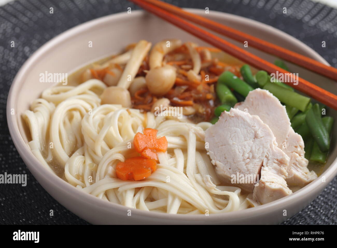Huhn und Udon Noodle Soup mit Shimeji Champignons, Karotten, Zwiebeln, Spargel Bohnen Stockfoto