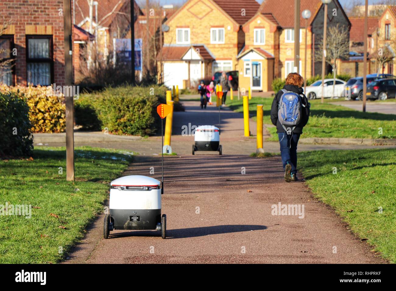 Fußgänger gehen Sie über Ihren Alltag als Starship autonomen Technologien Roboter routine Lebensmittellieferung rund um Milton Keynes. Stockfoto