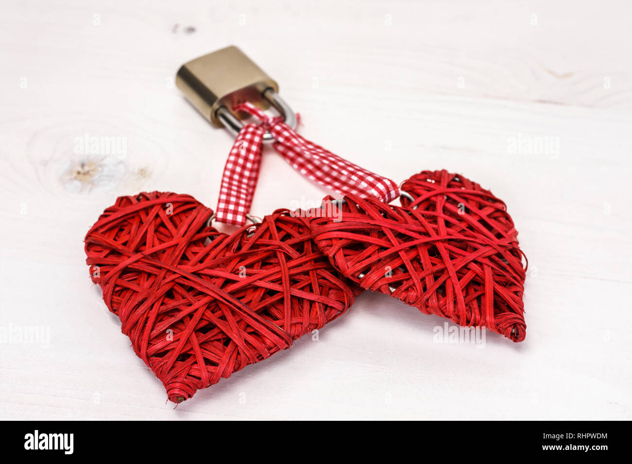 Zwei rote Herzen mit einem Vorhängeschloss an einem weißen Holz- Hintergrund gesperrt. Valentines Tag Konzept. Stockfoto