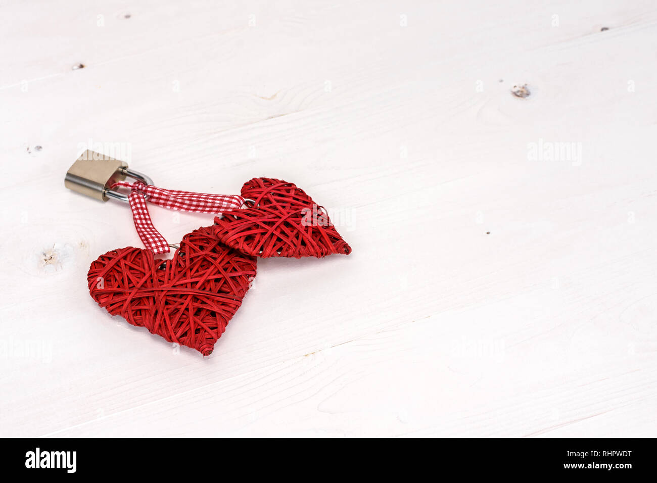 Zwei rote Herzen mit einem Vorhängeschloss an einem weißen Holz- Hintergrund gesperrt. Valentines Tag Karte Konzept. Stockfoto