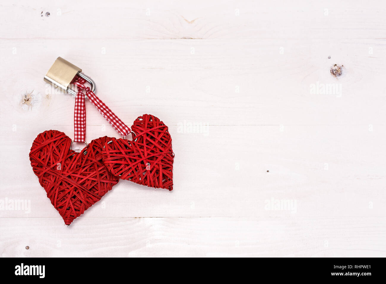 Zwei rote Herzen mit einem Vorhängeschloss an einem weißen Holz- Hintergrund gesperrt. Valentines Tag Karte Konzept. Stockfoto