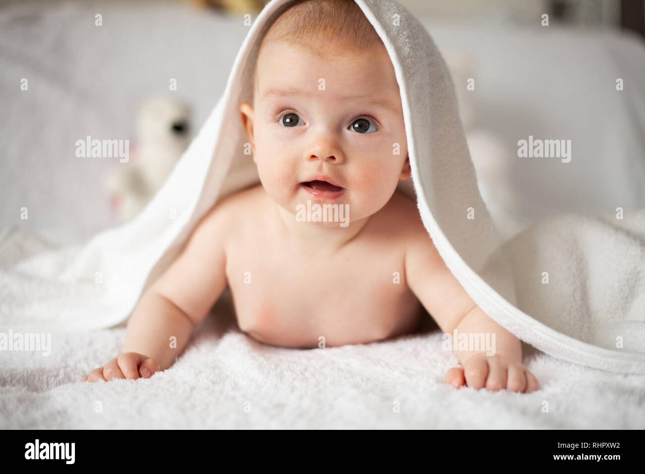 Baby Mädchen versteckt sich unter der weißen Decke. Stockfoto
