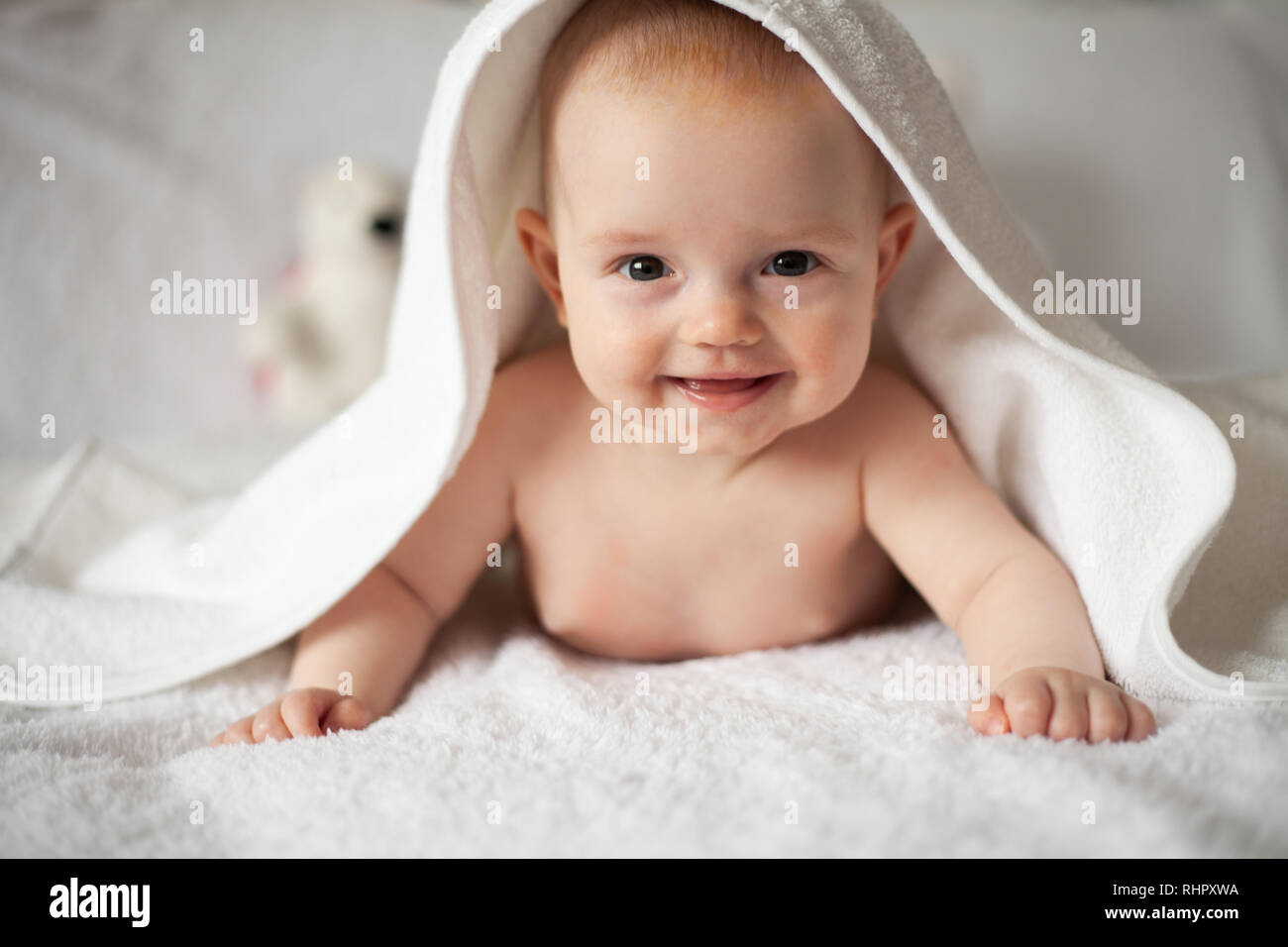 Baby Mädchen versteckt sich unter der weißen Decke. Stockfoto