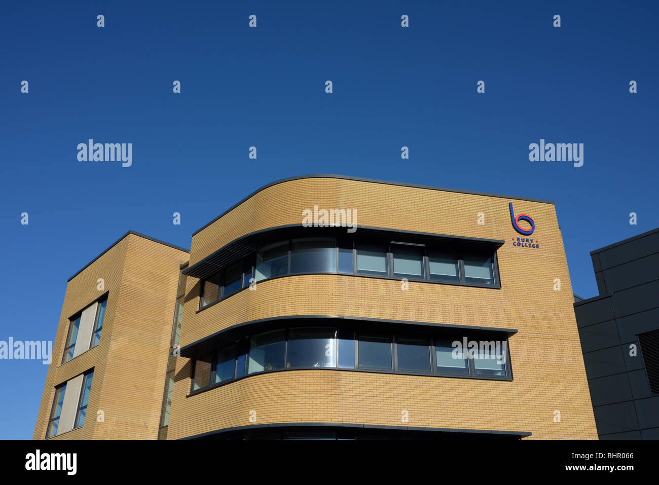 Modernes Gebäude mit geschwungener Fassade, buff Mauerwerk und gebogenen Band-Fenster mit Sonnenschutz in klaren blauen Himmel ohne Wolken in Bury lancashire uk Stockfoto