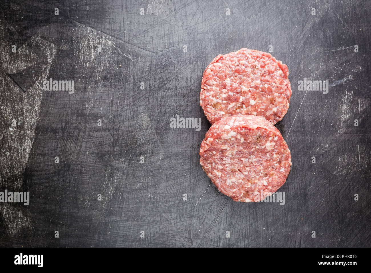 Frische rohe Prime Black Angus Beef Burger Pastetchen auf schwarzem Hintergrund. Ansicht von oben. Stockfoto