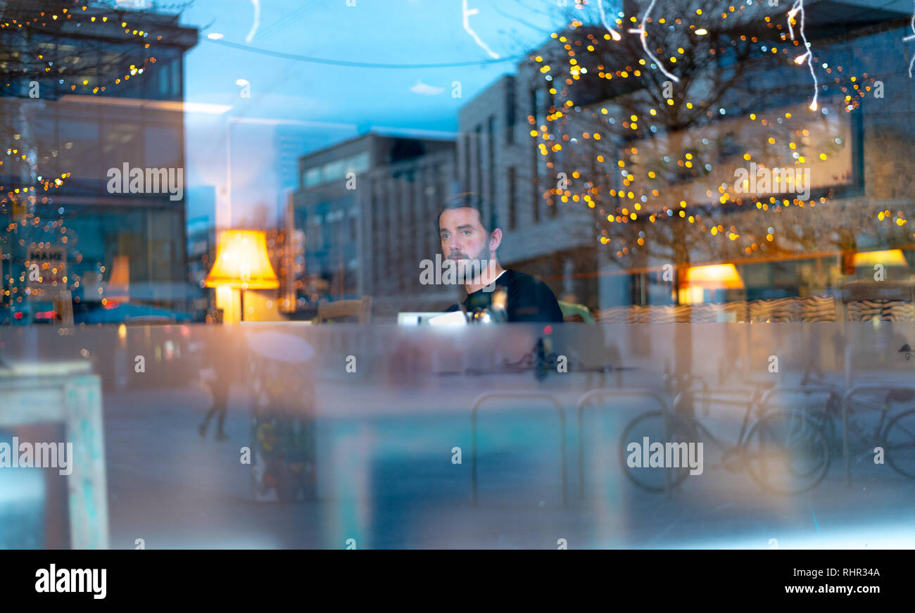 Stattlicher Mann mit Bart in Coffee Shop mit Licht reflektierenden Stockfoto