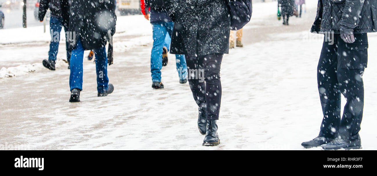 Winter Stadt rutschigen Bürgersteig. Zurück Blick auf die Füße von Menschen zu Fuß entlang der eisigen verschneiten Pflaster. Paar Schuh auf vereisten Straße im Winter. Abstrakte zuvorzukommen. Stockfoto