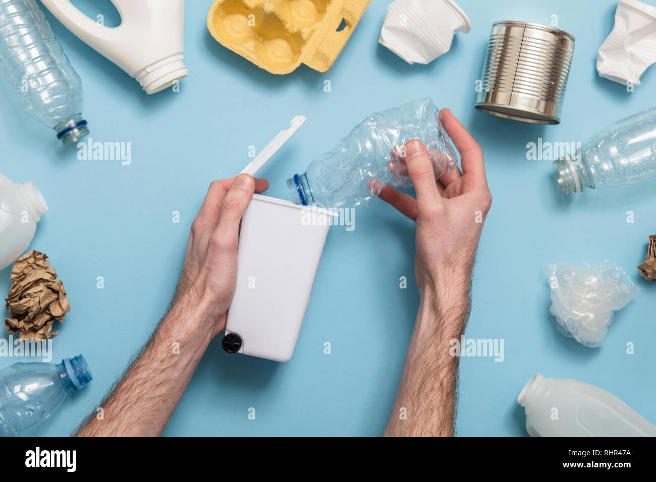 Hand mit einem Recycling Mülleimer mit viel Verpackungsmüll Stockfoto