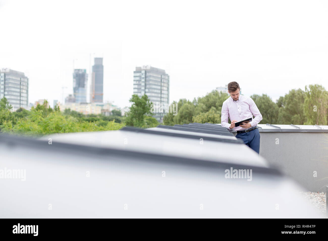 Mit digitalen Tablet während auf Stützmauer auf der Terrasse schiefen Geschäftsmann Stockfoto