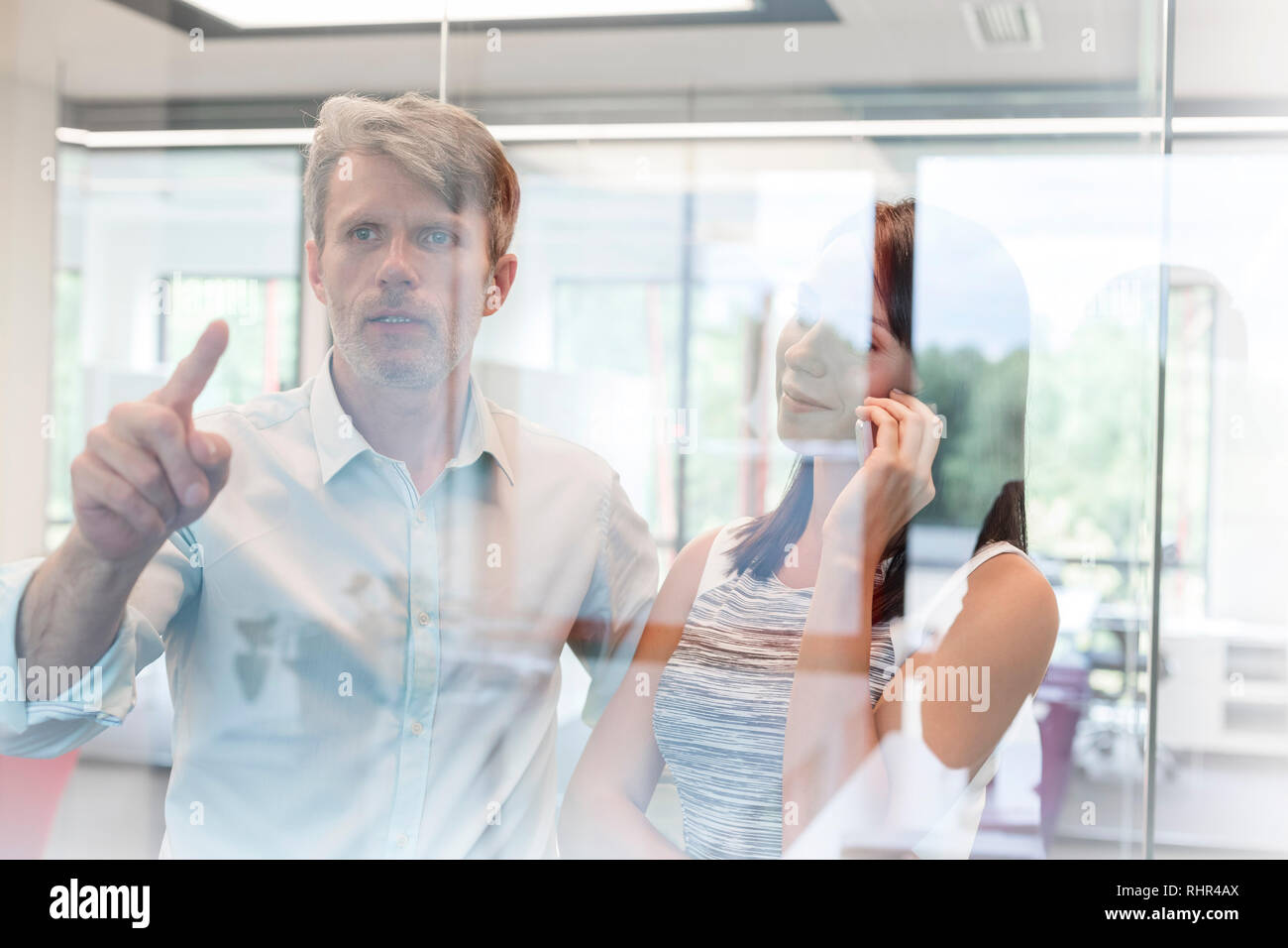 Geschäftsfrau, Reden auf dem Smartphone beim Stehen mit Kollegen im Büro Stockfoto