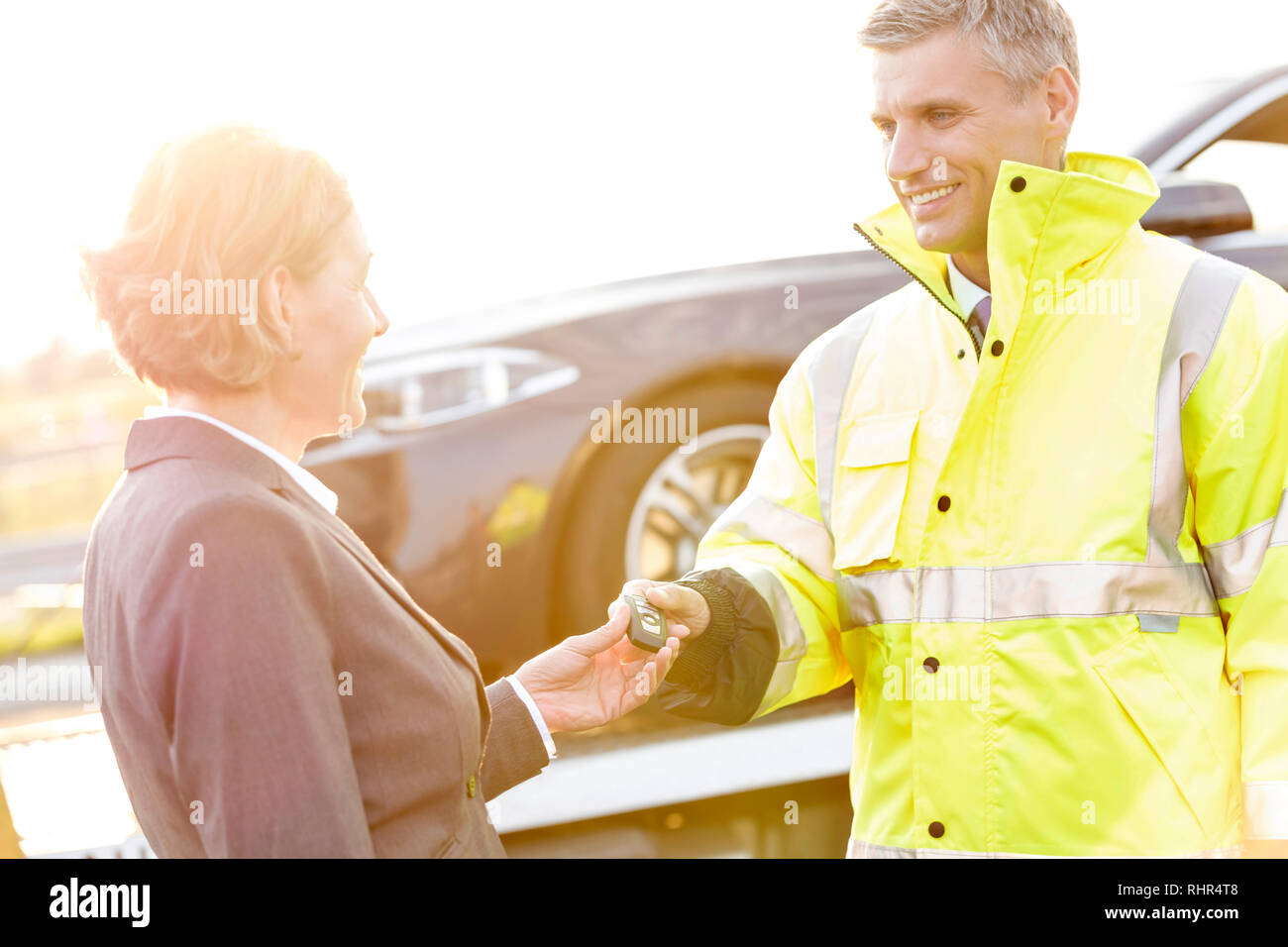 Lächelnd Abschleppwagen Fahrer mit Auto Schlüssel zur geschäftsfrau Stockfoto