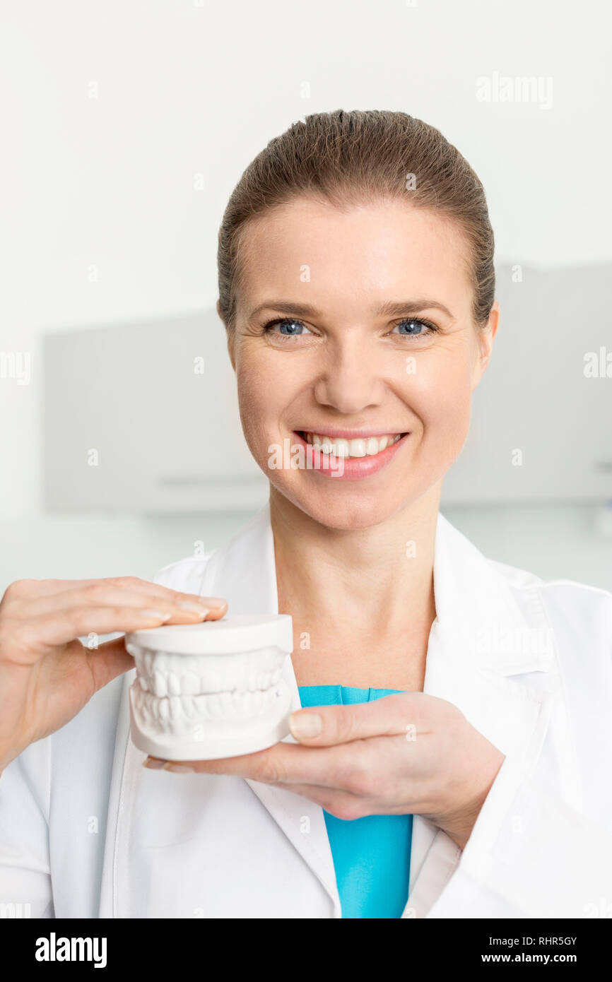 Portrait von lächelnden Zahnarzt holding Zahnersatz an der Klinik Stockfoto