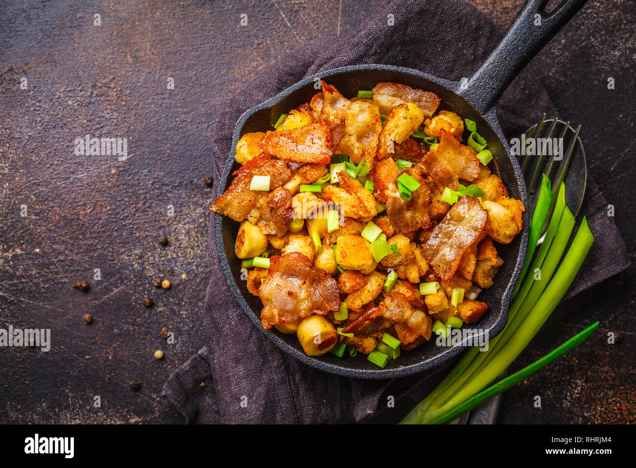 Spanisch migas mit Schweinefleisch und grüne Zwiebeln in einer gusseisernen  Pfanne auf einem dunklen Hintergrund Stockfotografie - Alamy