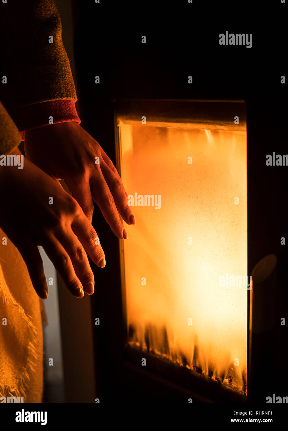 Mädchen ist Heizung Hände durch den Ofen zu hören. Stockfoto