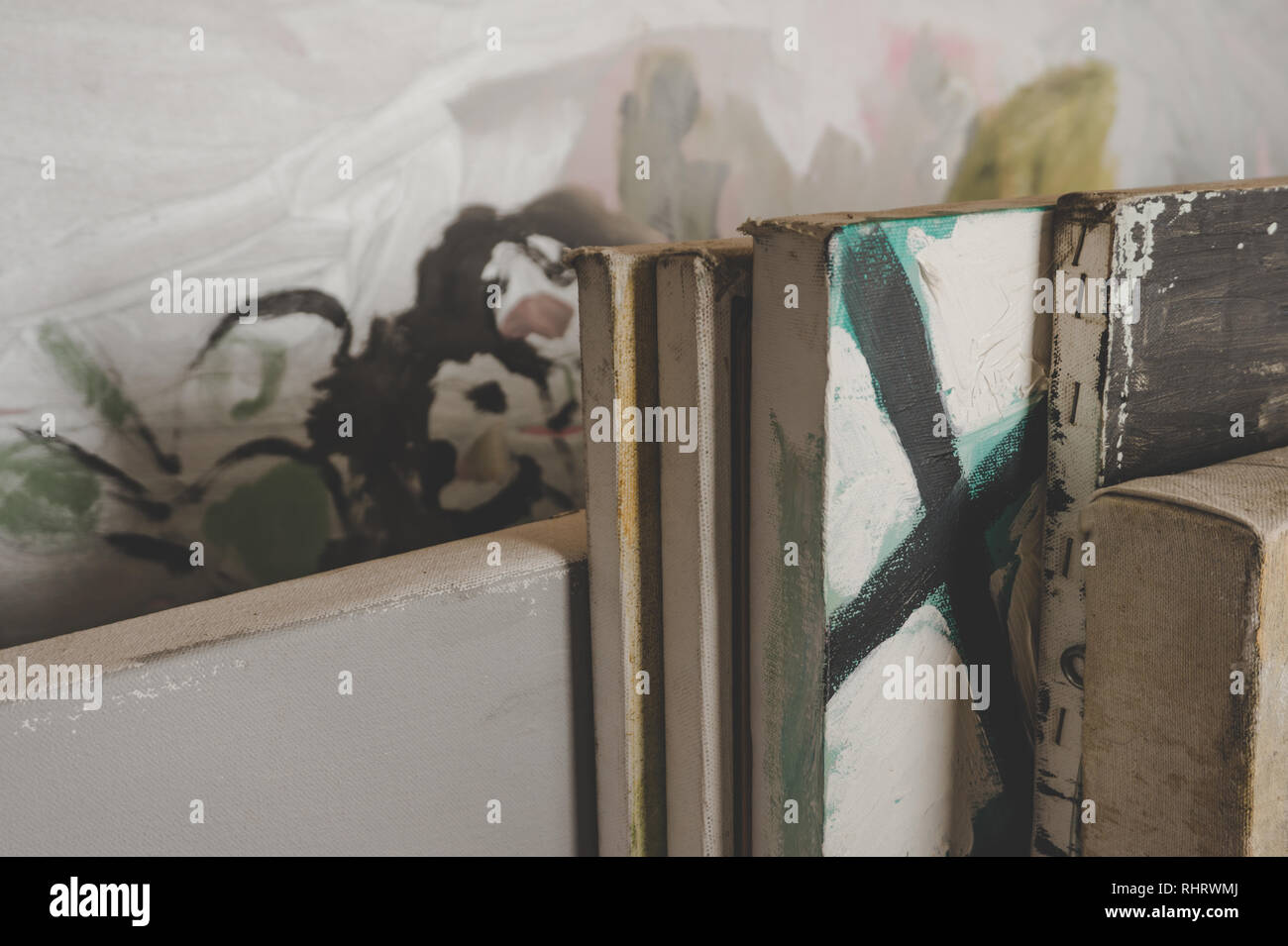 Kunst Gemälde auf Leinwand im Atelier eines Künstlers gestapelt -- Close up gesehen mit stimmungsvoller Beleuchtung Stockfoto