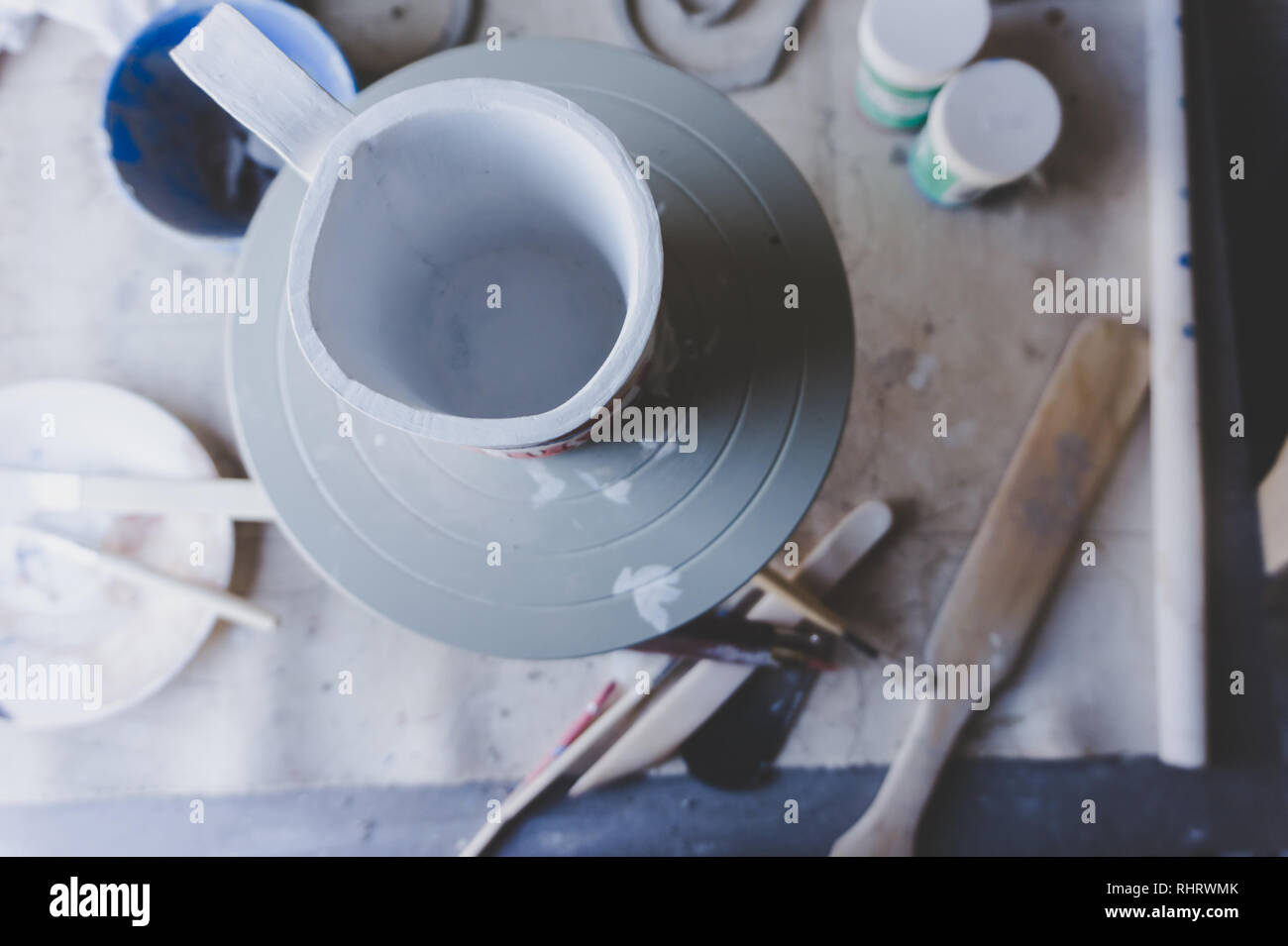 Keramik Studio mit in Arbeit von oben gesehen: ein Becher auf einer Verzierung Rad, Glasuren und anderen Tools Stockfoto