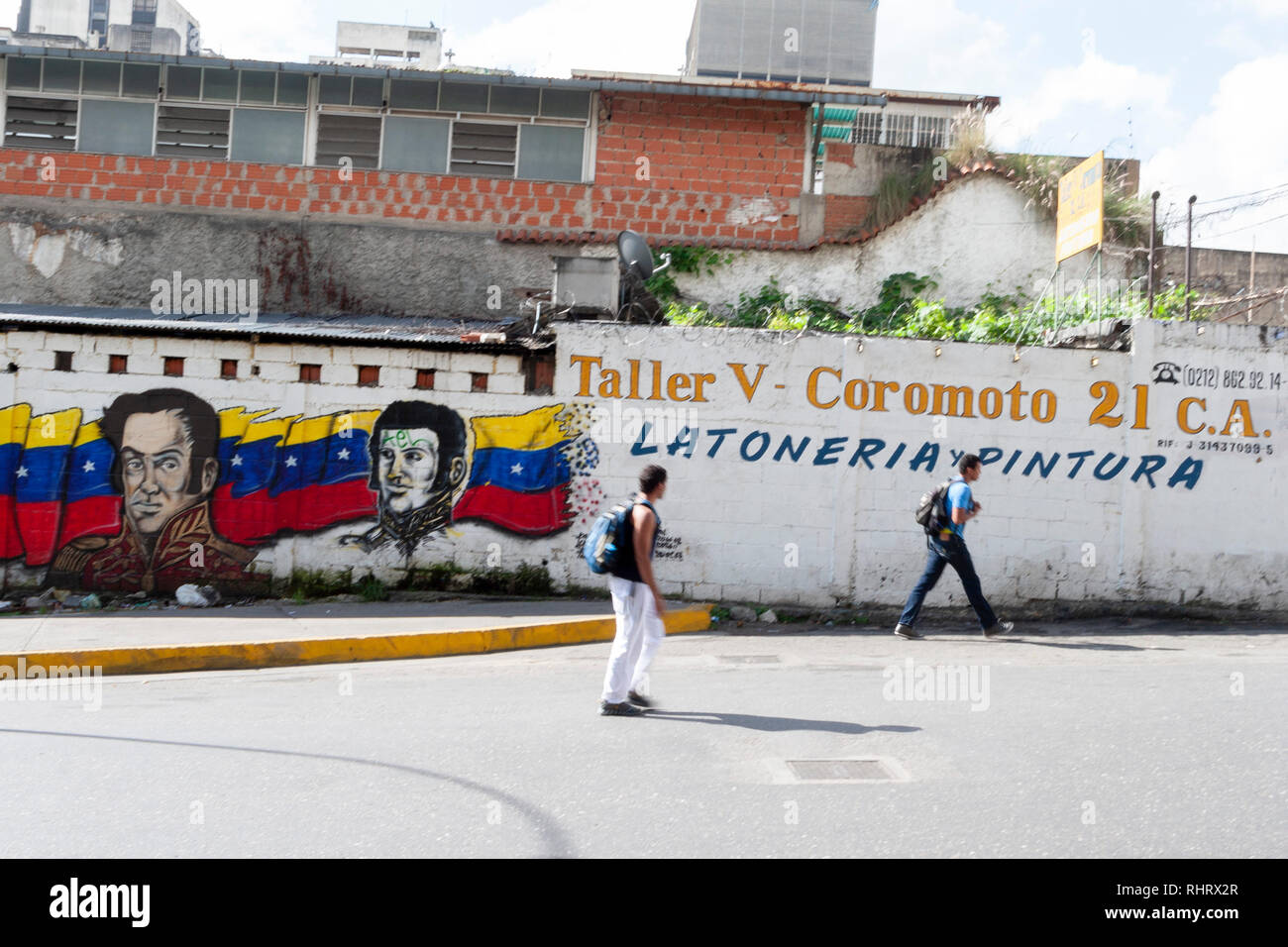 Venezuela Caracas 21/01/2012. Zwei Mann mit einer politischen Wandbild auf Hintergrund in La Pastora Nachbarschaft. Stockfoto