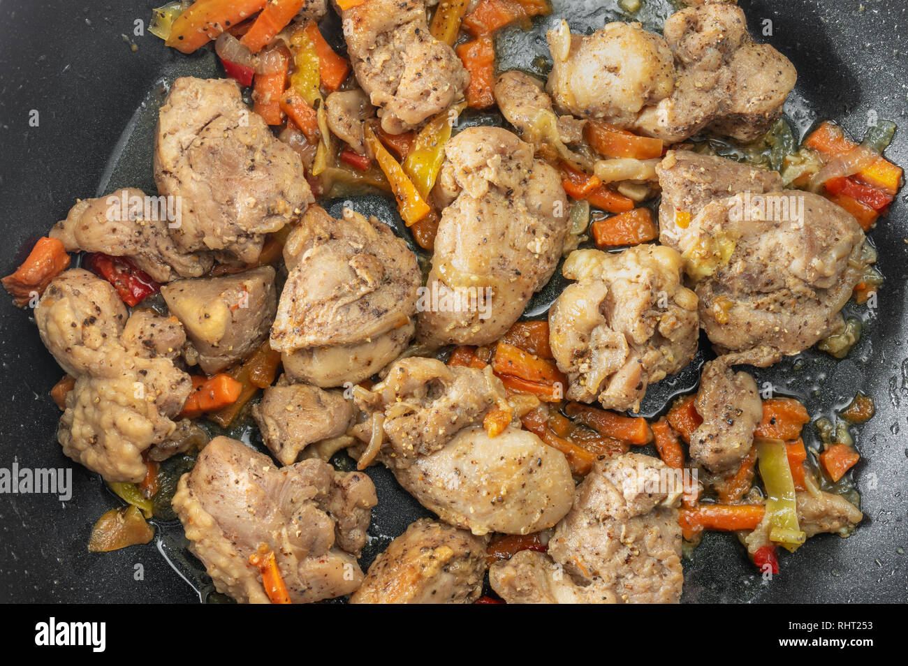 Ansicht von oben auf eine Pfanne mit Putenfleisch Stücke gebraten in Sonnenblumenöl und Gemüse Stockfoto