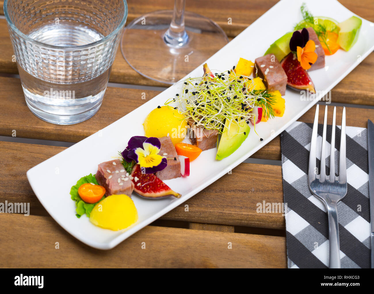 Teller mit leckeren gebratenen Thunfisch mit Mango, Avocado und Feigen auf lange Platte serviert Stockfotografie