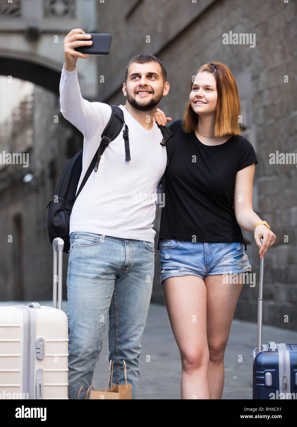 Lächelnd russische weibliche und männliche stehend mit Gepäck auf der Straße und Unter selfie Stockfoto
