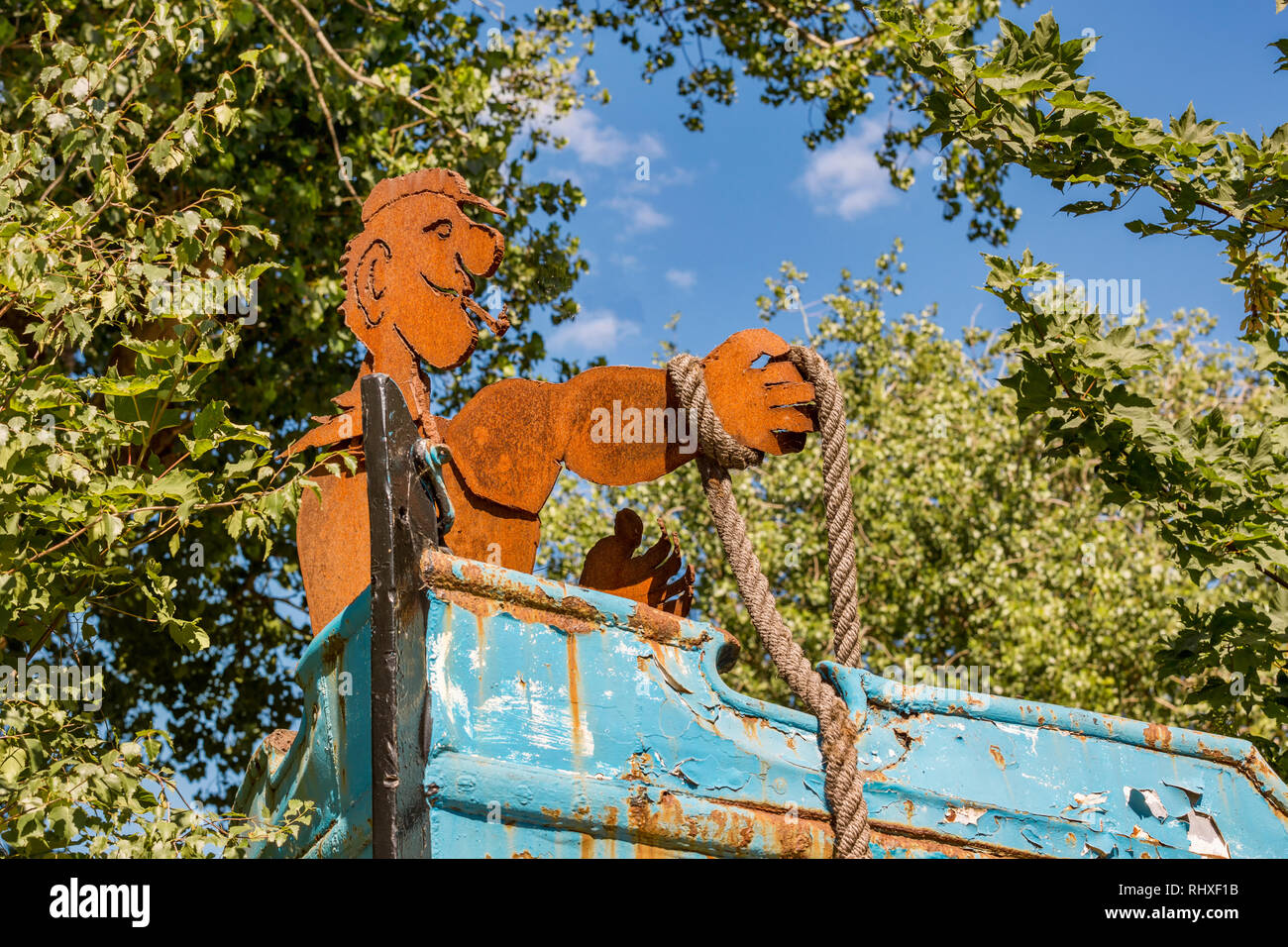 Rusty männliche Figur mit Tau in der Hand auf einem kleinen Boot Stockfoto