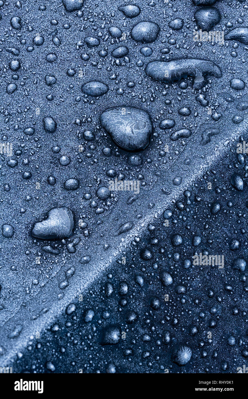 Gefrorene Wassertropfen auf einem schwarzen Auto. Stockfoto
