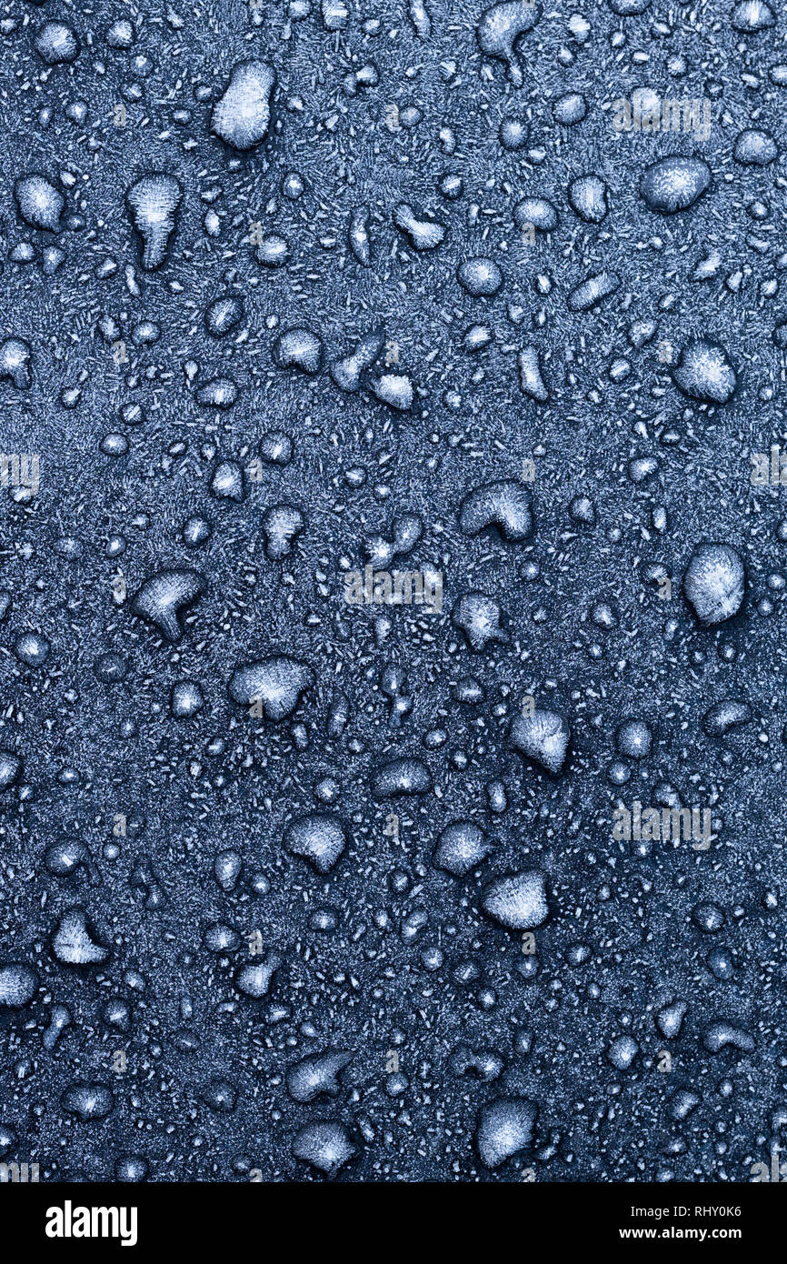 Gefrorene Wassertropfen auf einem schwarzen Auto. Stockfoto