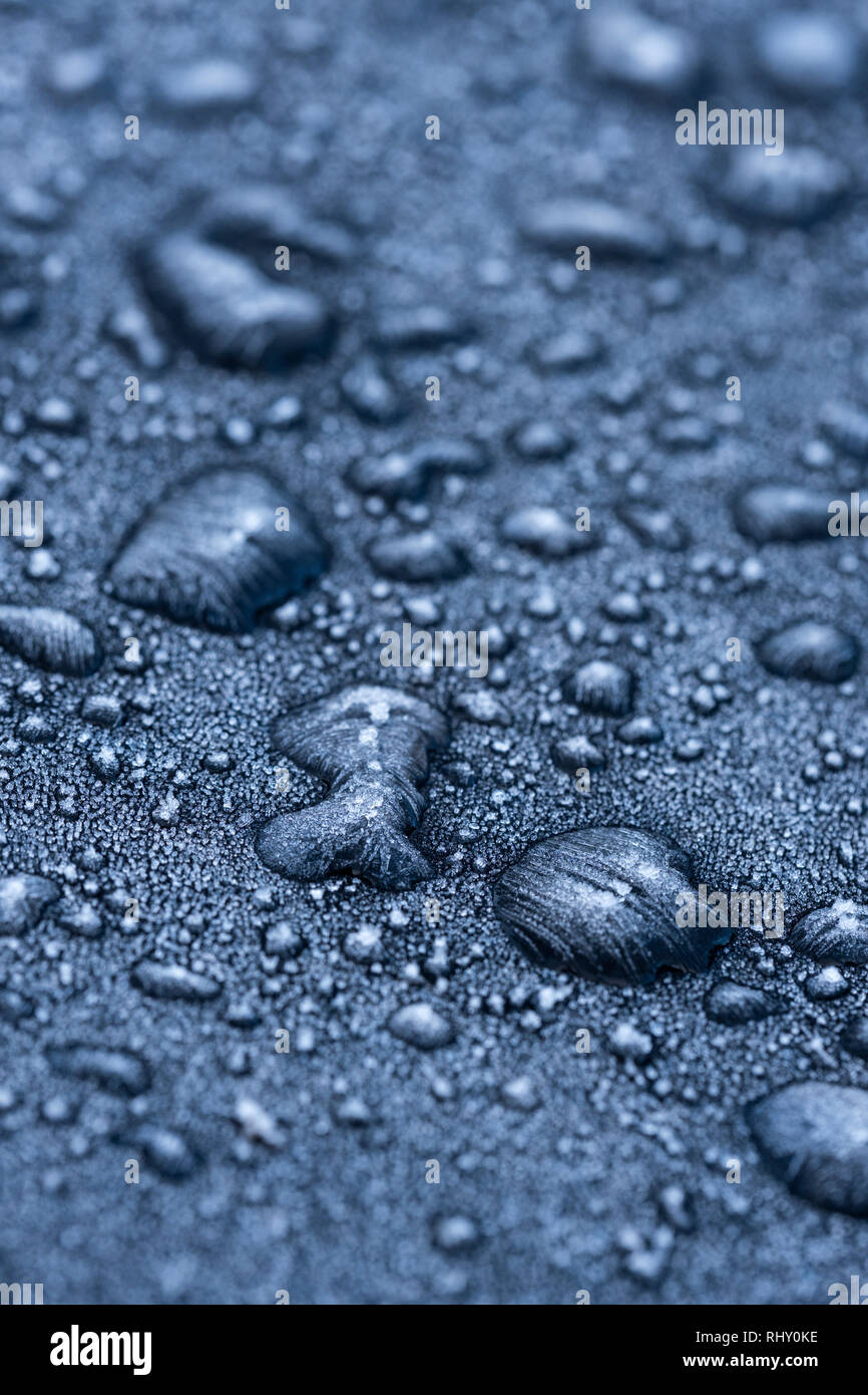 Gefrorene Wassertropfen auf einem schwarzen Auto. Stockfoto