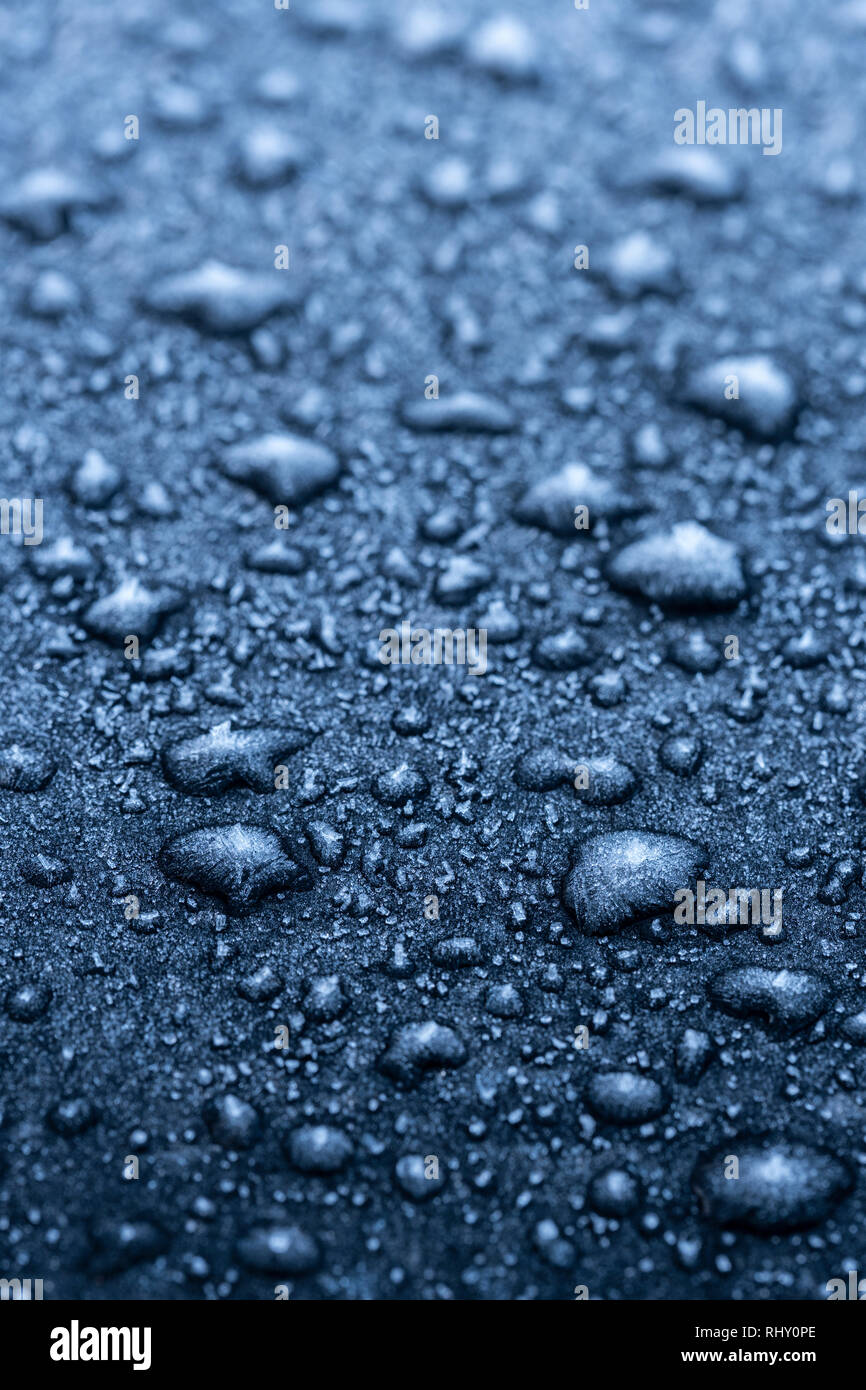 Gefrorene Wassertropfen auf einem schwarzen Auto. Stockfoto