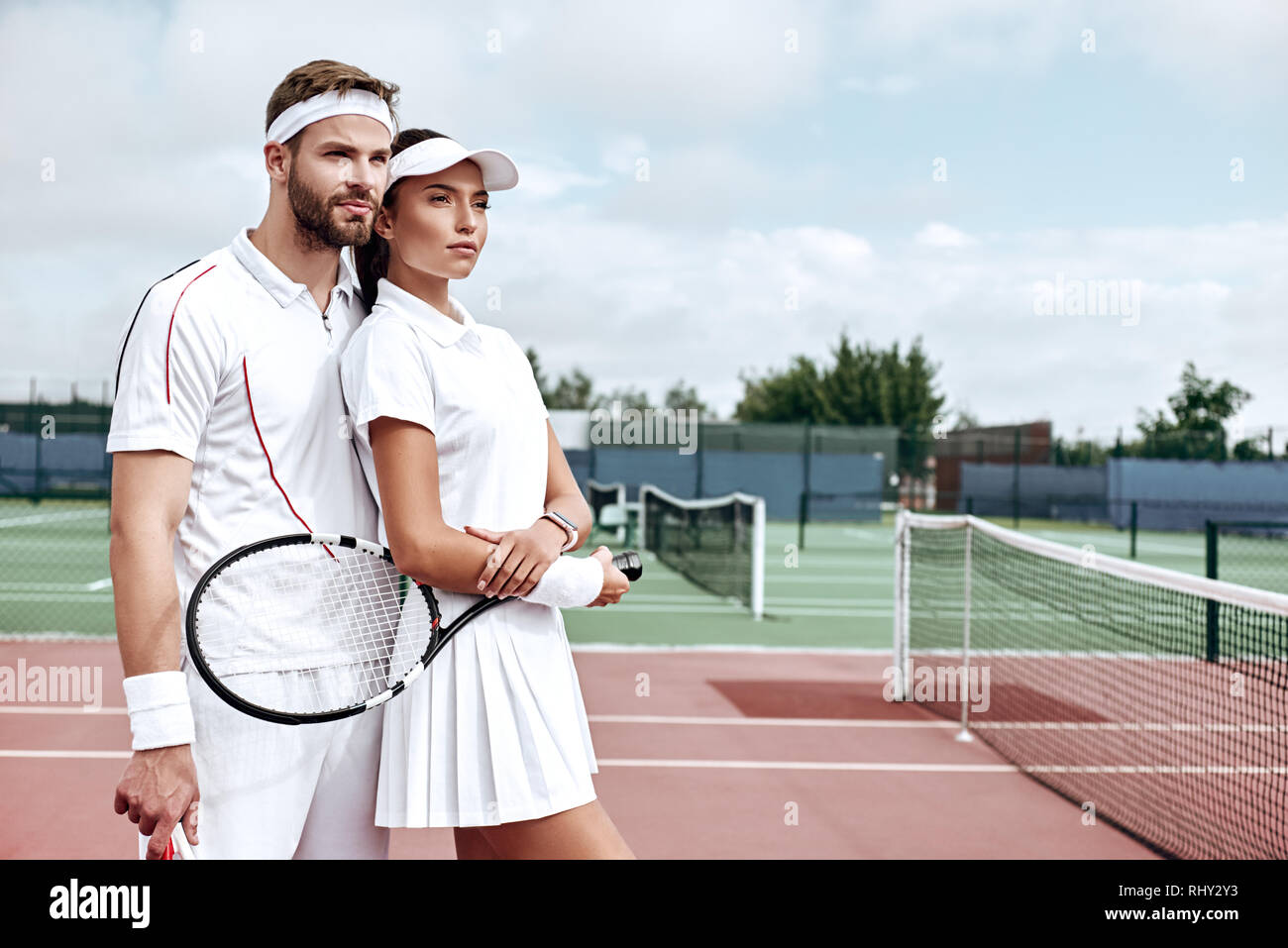 Schöner Mann und attraktive Frau in Weiß Sportswear stehen auf dem Hof weg schauen Stockfoto