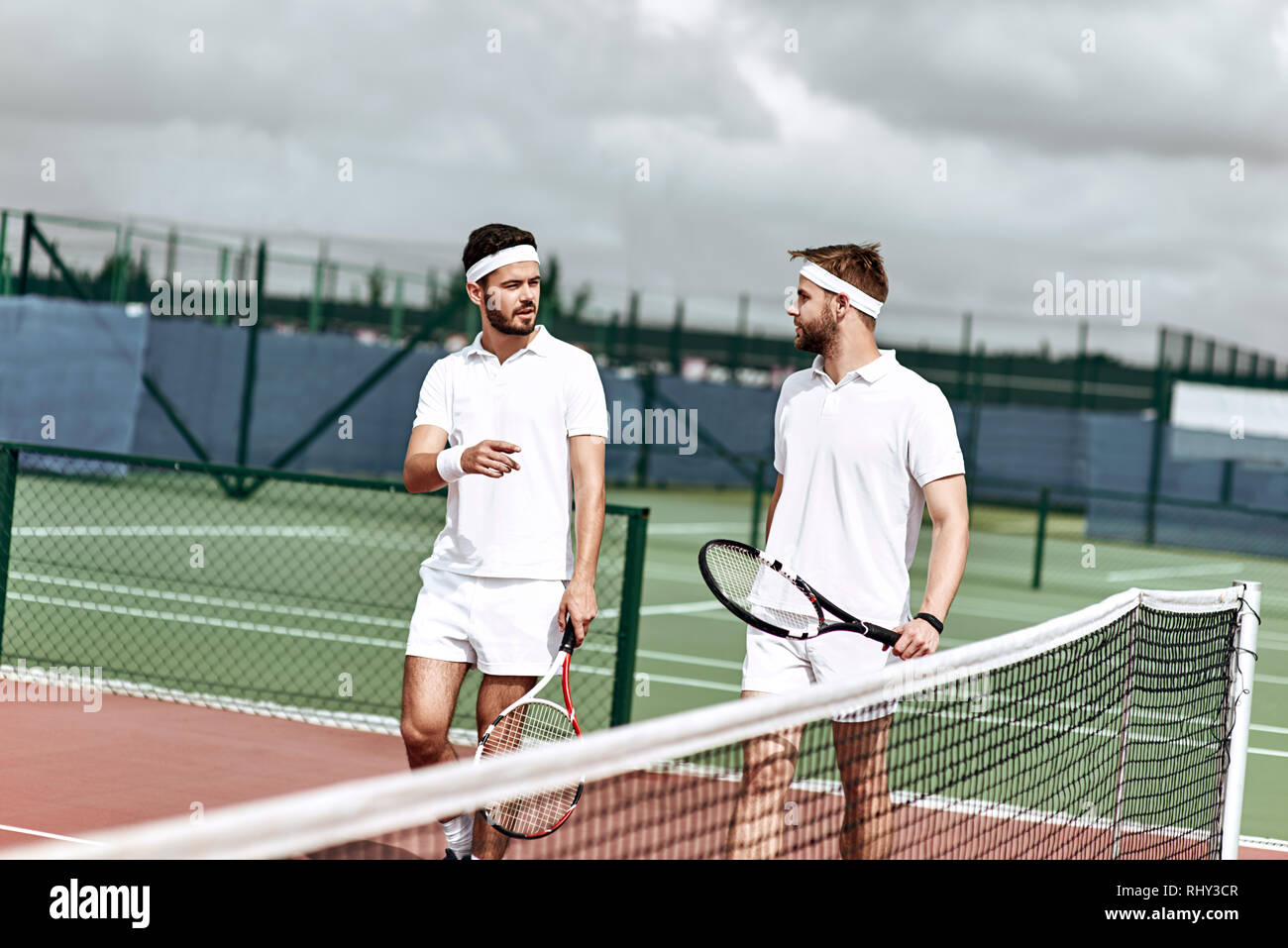 Stattliche Tennisspieler in Weiß Sportswear diskutieren die anstehenden Spiel Stockfoto