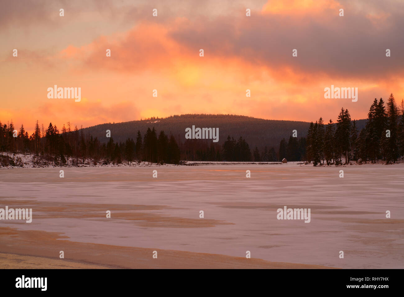 Sonnenuntergang über einem verschneiten See im Wald. Winterlandschaft in schönen Pastellfarben, See Oderteich, Nationalpark Harz, Niedersachsen, Deutschland. Stockfoto