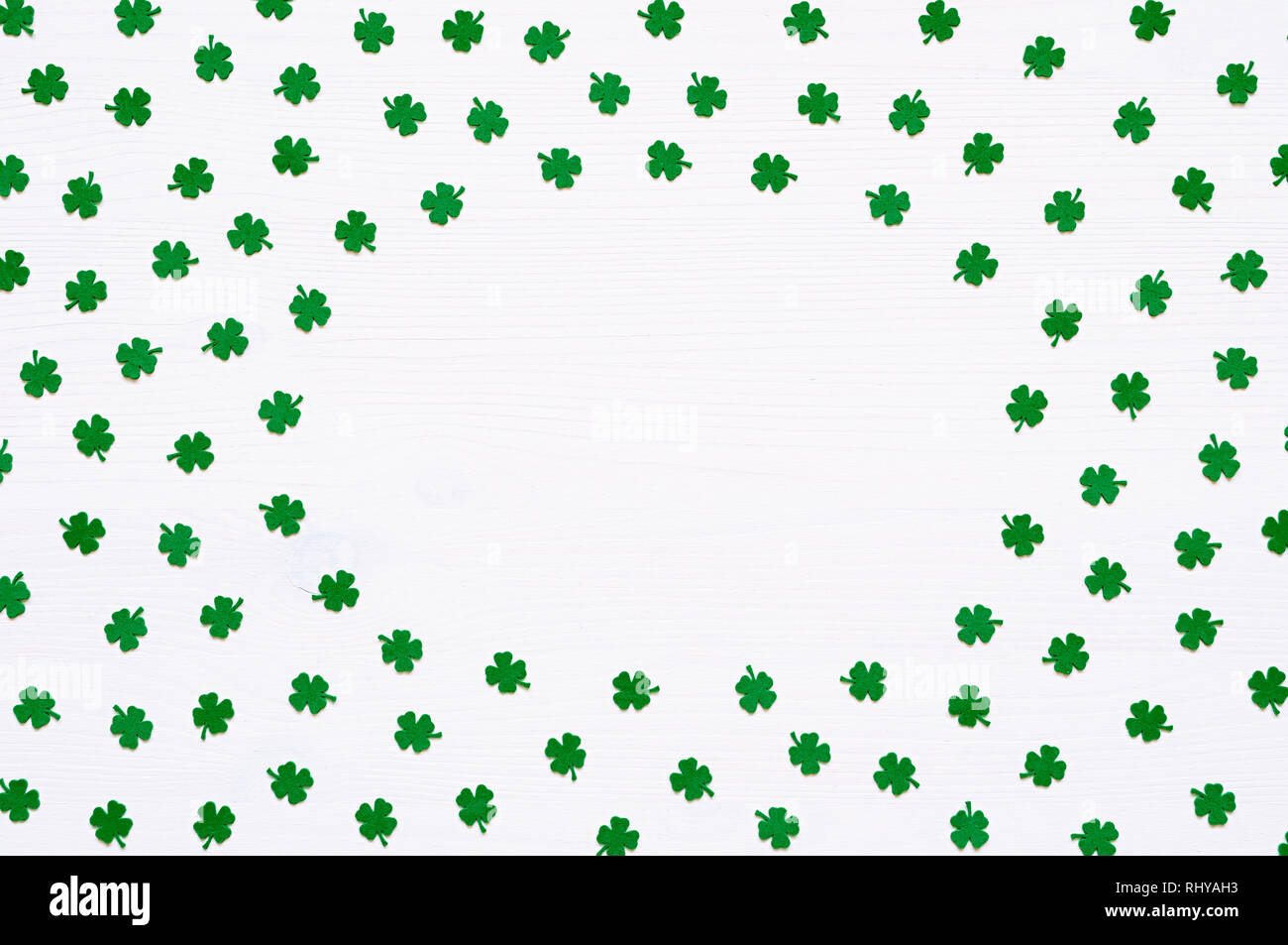 St Patrick's Day Hintergrund. Grüne quatrefoils auf dem weißen Holz- Oberfläche mit freier Platz für Text, runden Rahmen Grenze Stockfoto