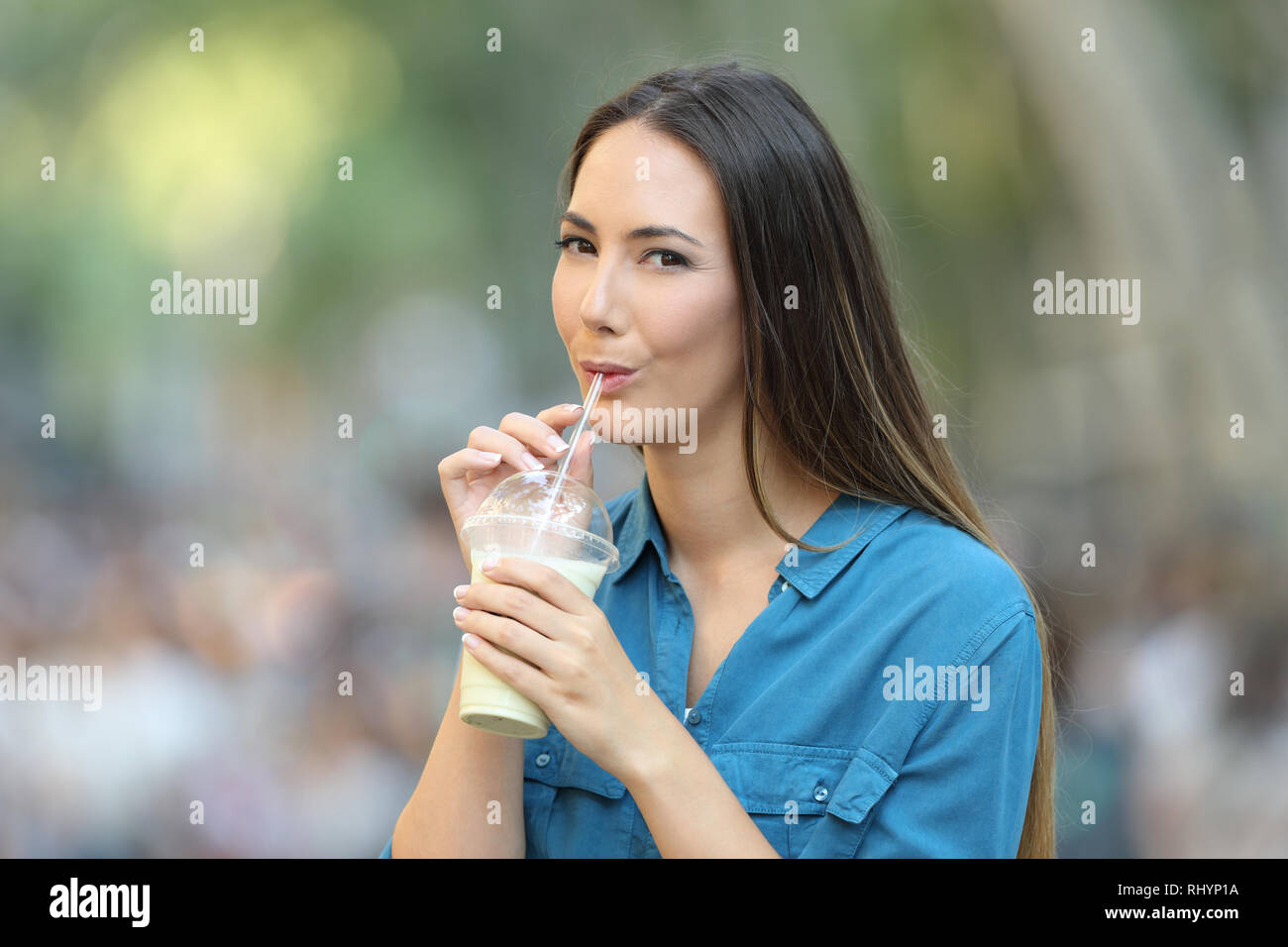 Gerne Frau trinkt Milch Shake mit einem Stroh auf der Straße auf Sie auf der Suche Stockfoto
